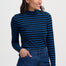 Woman wearing a blue and black striped long-sleeve top and blue jeans against a white background