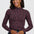 A woman wearing a dark brown mock neck long-sleeve top with a pink leopard print pattern, paired with blue jeans, against a light gray studio background.