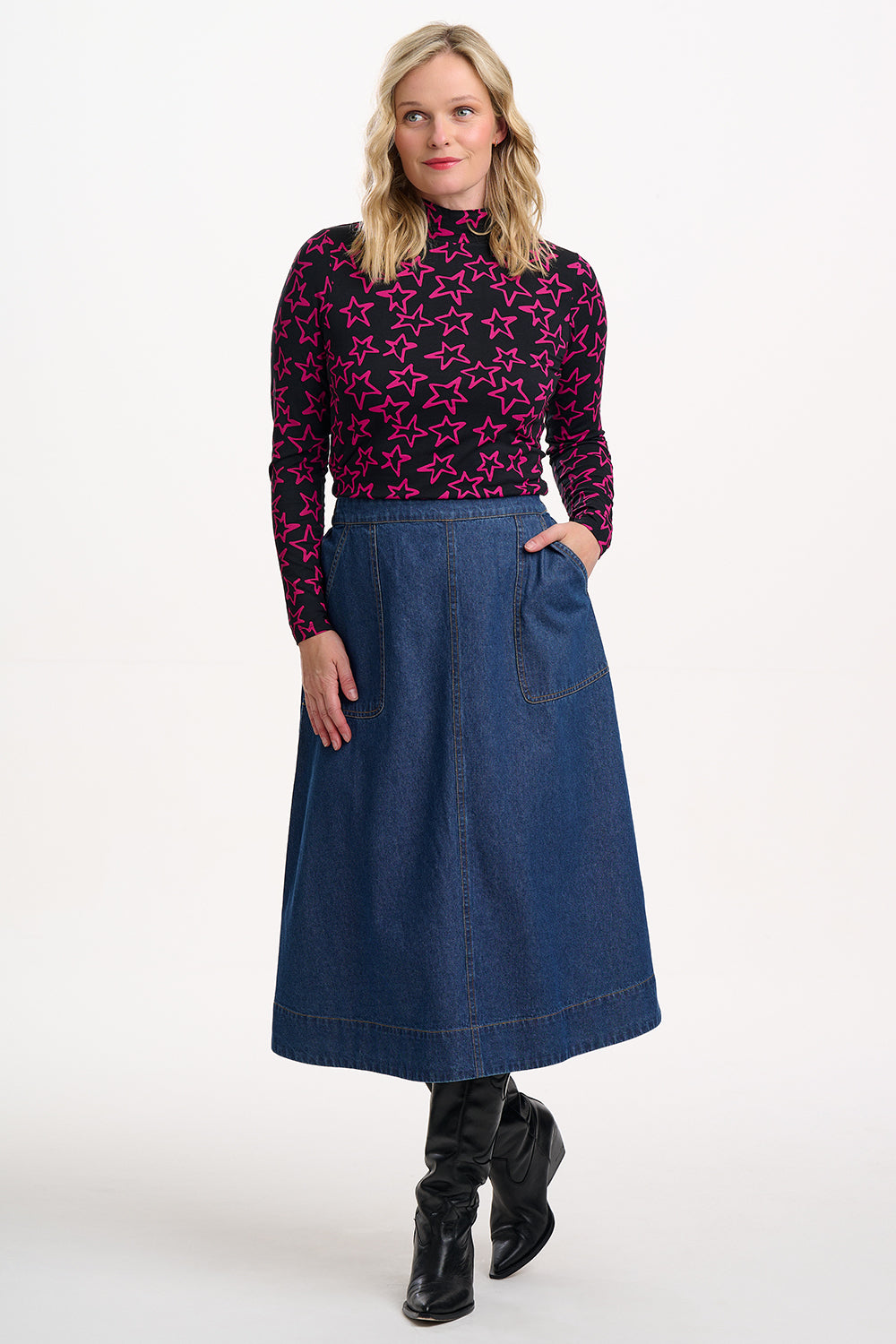 Woman wearing a patterned top and denim skirt on a white background
