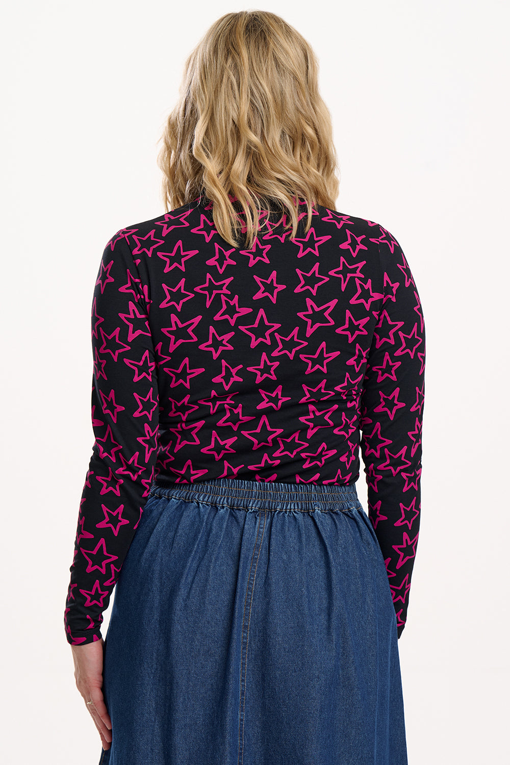 Person wearing a black long-sleeve top with pink star pattern and a blue skirt.