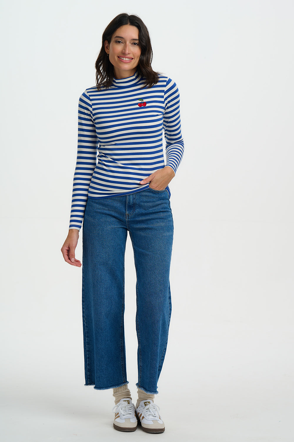 Woman wearing a blue and white striped shirt with a red heart and blue jeans on a white background