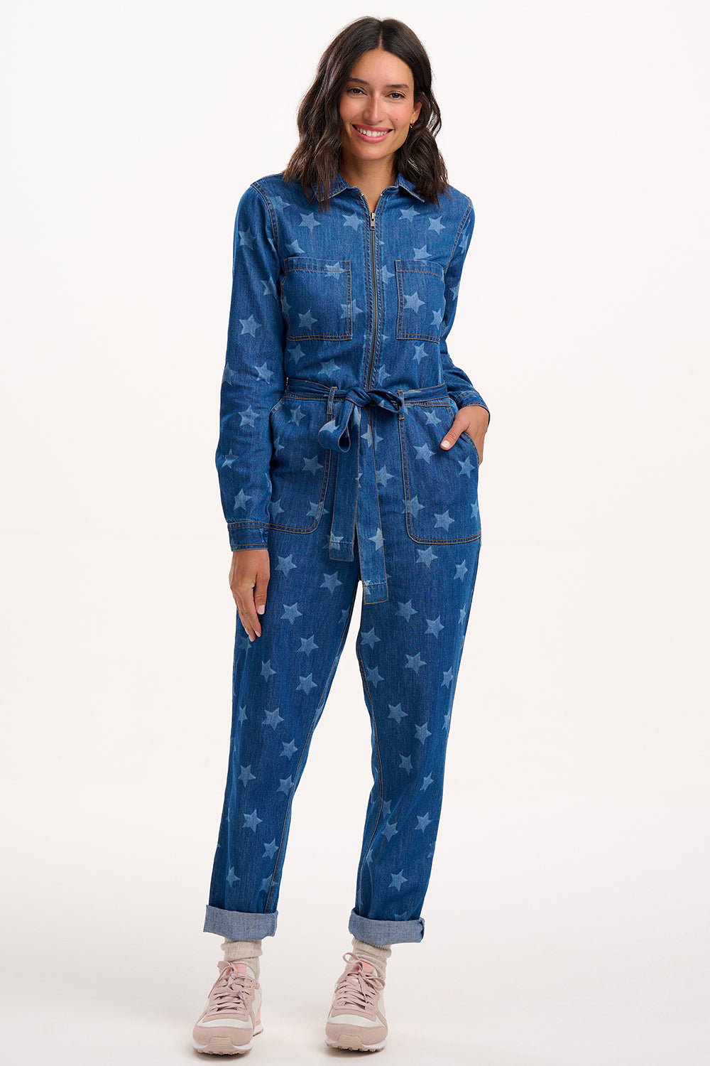 Woman wearing a blue denim jumpsuit with star pattern on a white background