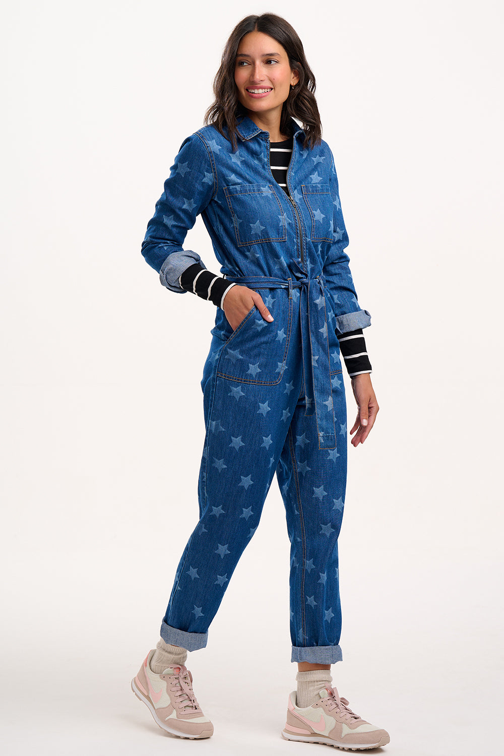 Woman wearing a blue denim jumpsuit with star patterns on a white background