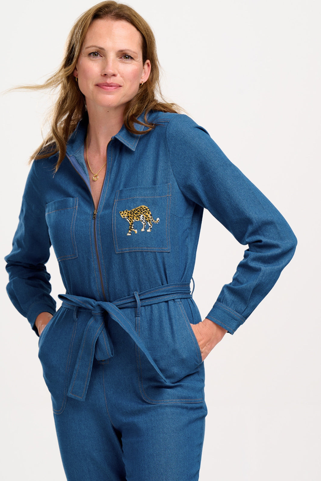 Woman wearing a blue jumpsuit with a pocket design on a white background