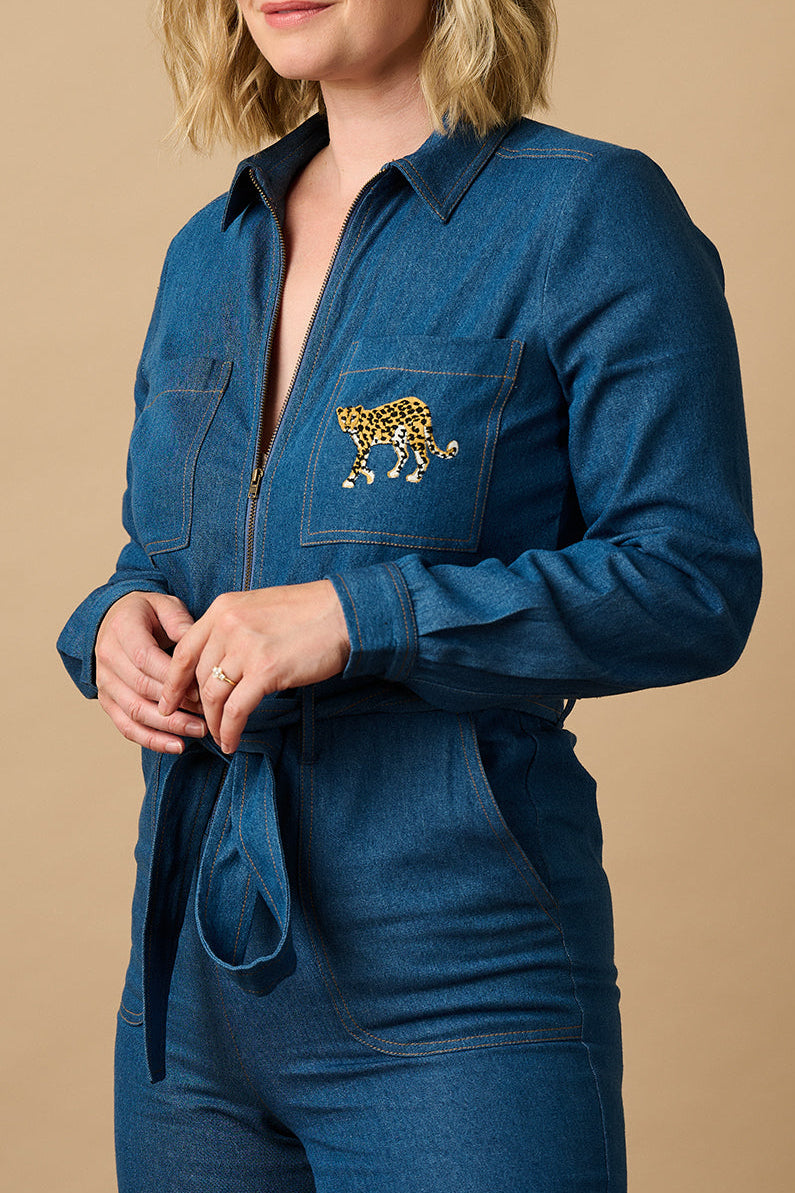 Person wearing a blue jumpsuit on a taupe background