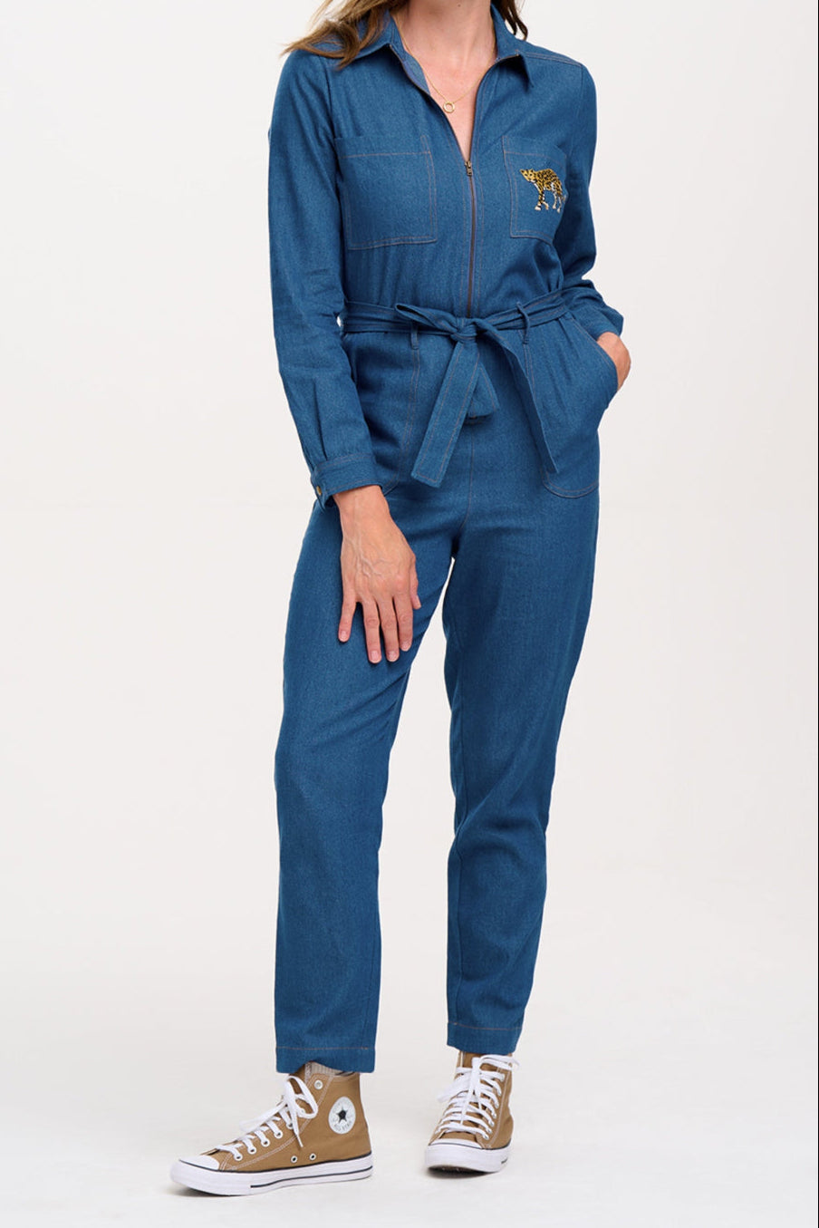 Woman wearing a blue jumpsuit with a logo on a white background