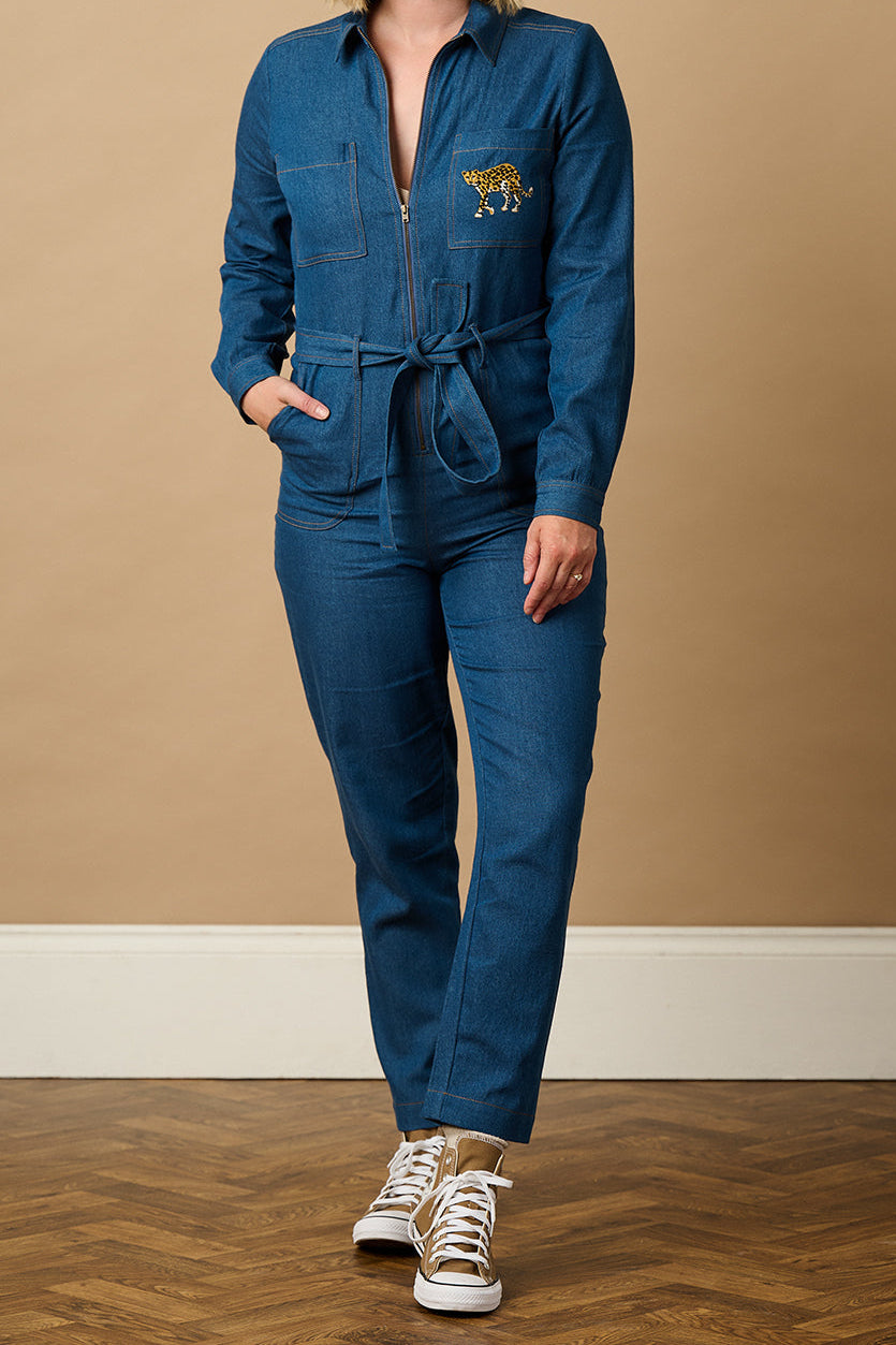 Person wearing a blue jumpsuit on a taupe background