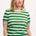 A woman wearing a green and white striped knit top with a crew neck and rainbow tipping on the cuffs and hem.