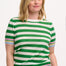 A woman wearing a green and white striped knit top with a crew neck and rainbow tipping on the cuffs and hem.