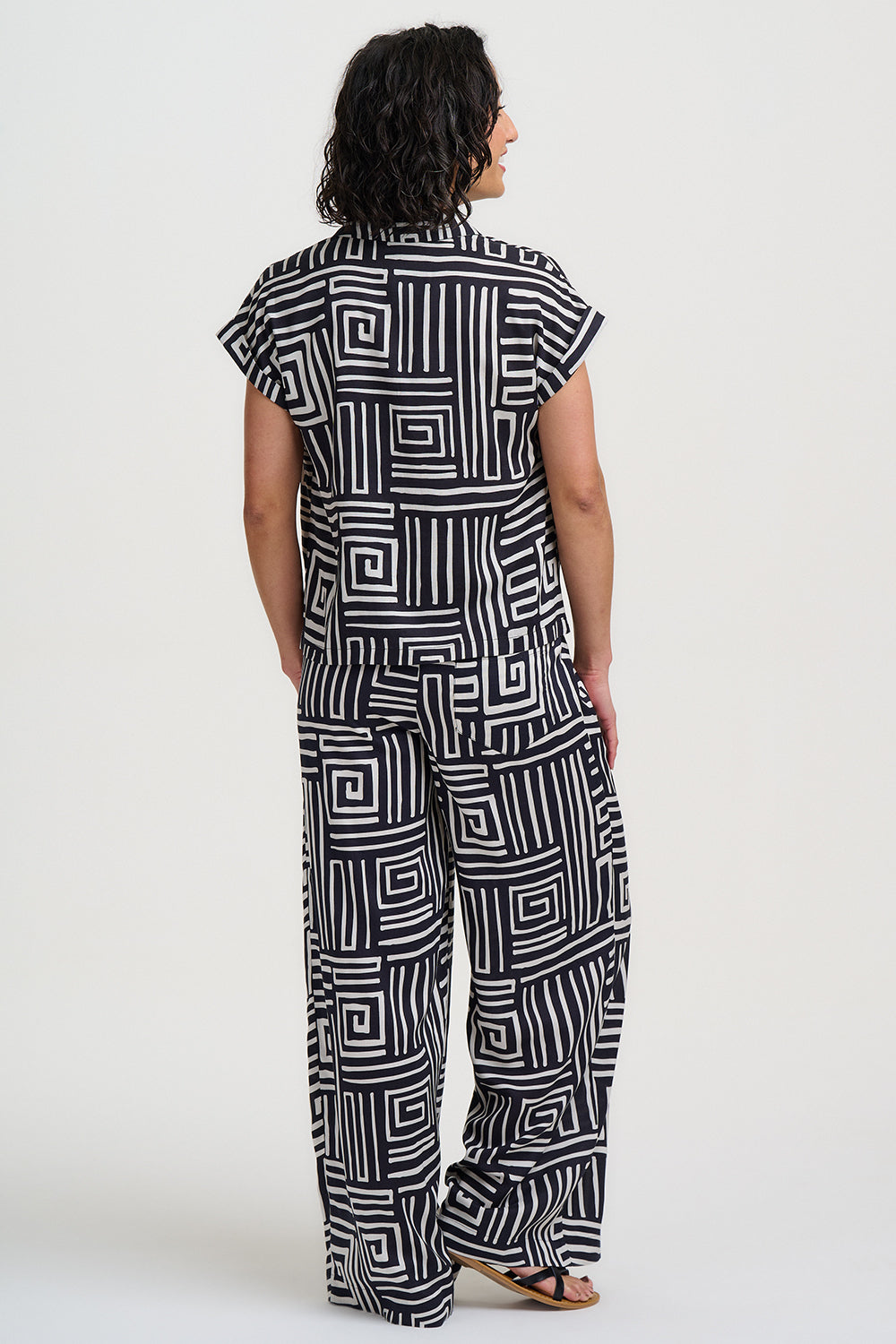 Person wearing a black and white geometric patterned jumpsuit on a white background