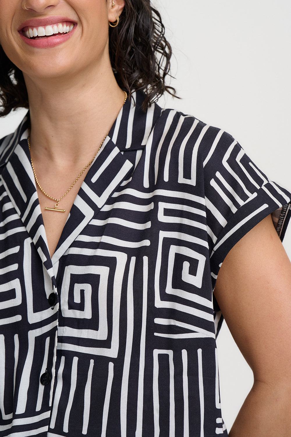 Woman wearing a black and white patterned shirt with a plain background