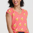 Woman wearing a pink shirt with banana print and blue shorts on a white background
