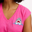 A woman wearing a pink V-neck tank t-shirt with a playful embroidered shark detail