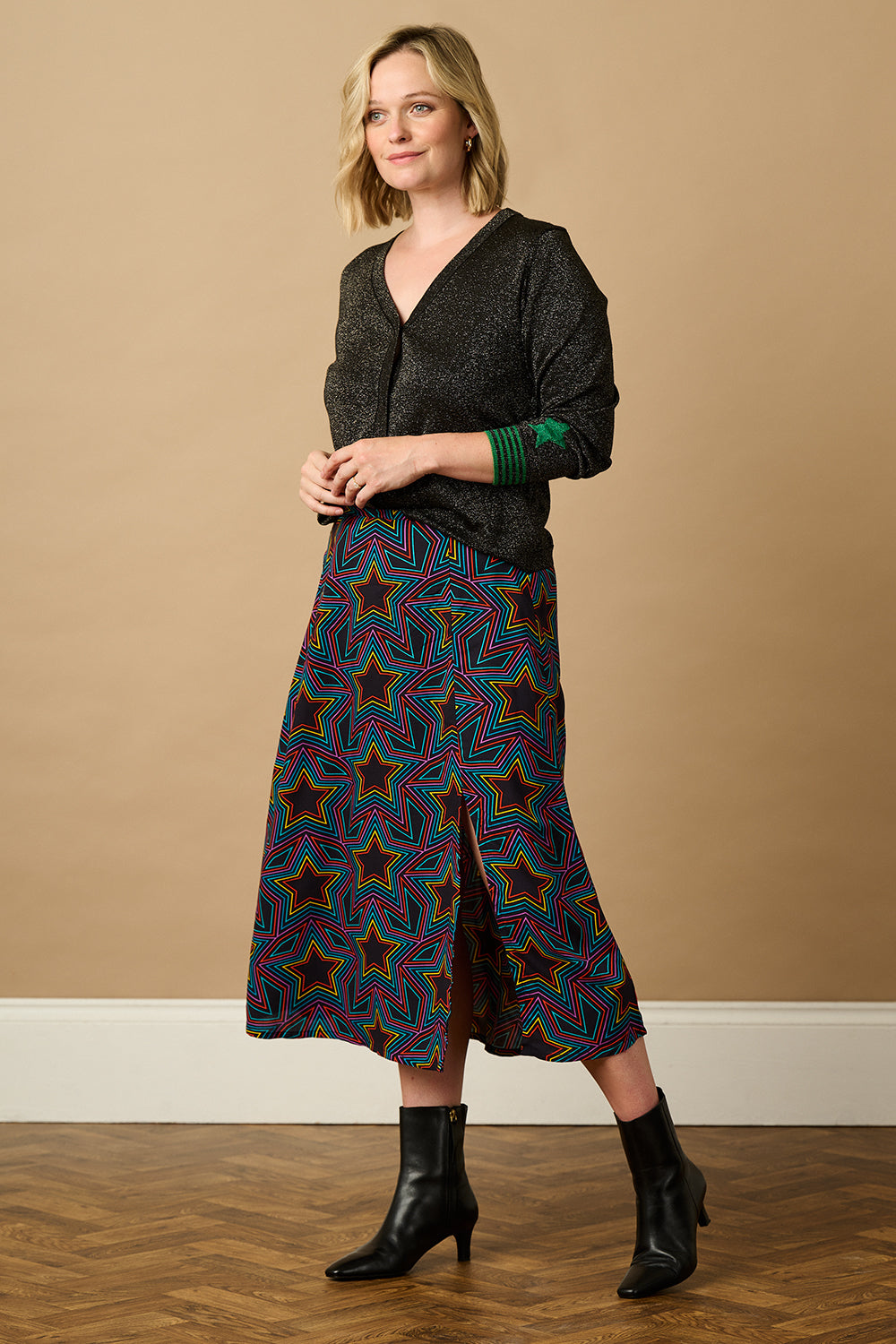 A black long-sleeve cardigan with green stripes and stars on the sleeves.