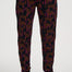 A person wearing black jogger-style pants with an allover leopard print in pink and orange, paired with white sneakers, shown from the waist down against a light gray studio background.
