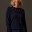 Woman wearing a dark sweater with pink lightning bolt patterns against a gray background