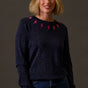 Woman wearing a dark sweater with pink lightning bolt patterns against a gray background