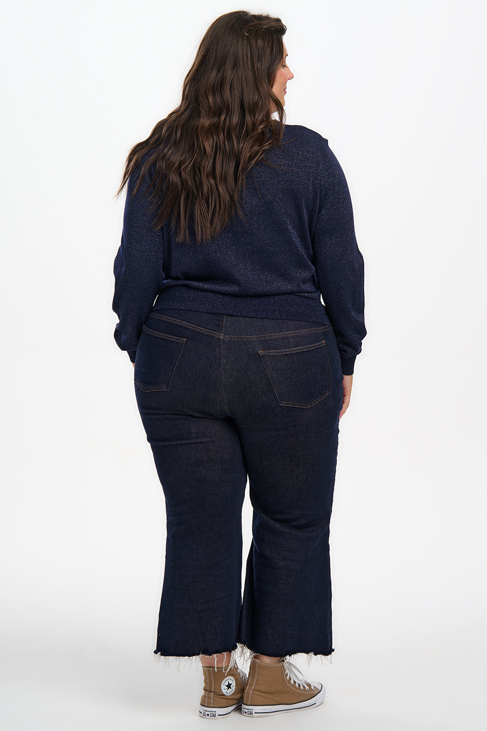 Person wearing a navy blue outfit with dark jeans and a matching top on a white background
