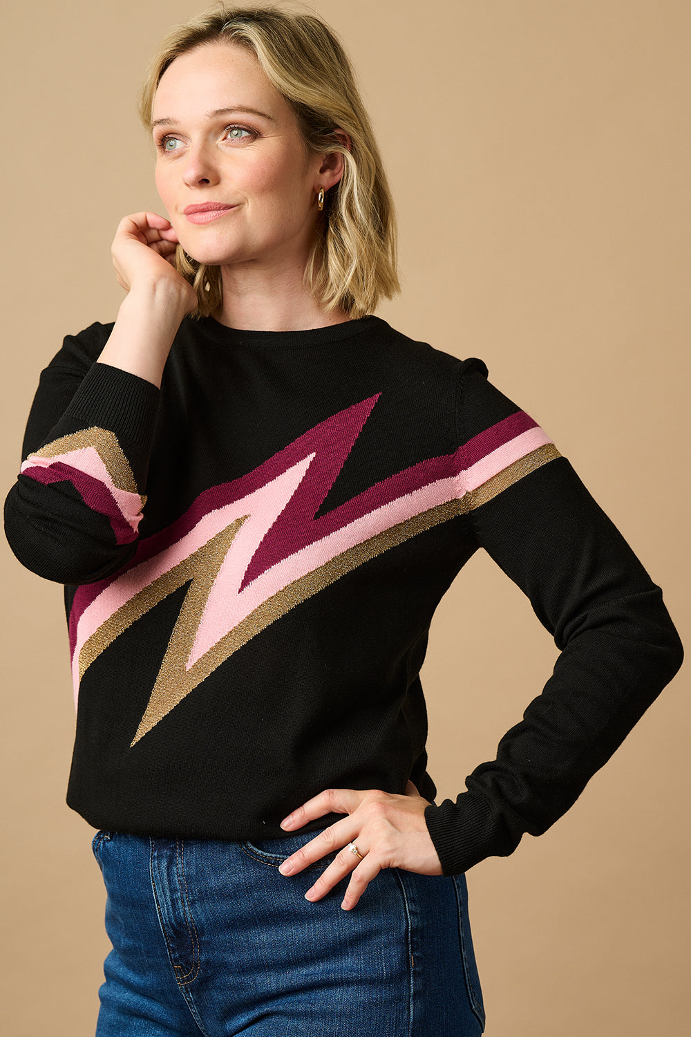 A female model wearing a black, berry and biscuit colored jumper with a crew neck and long sleeves.