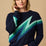 A woman wearing a long sleeve navy jumper with a graphic lightning bolt design in blue and green across the torso and arms.