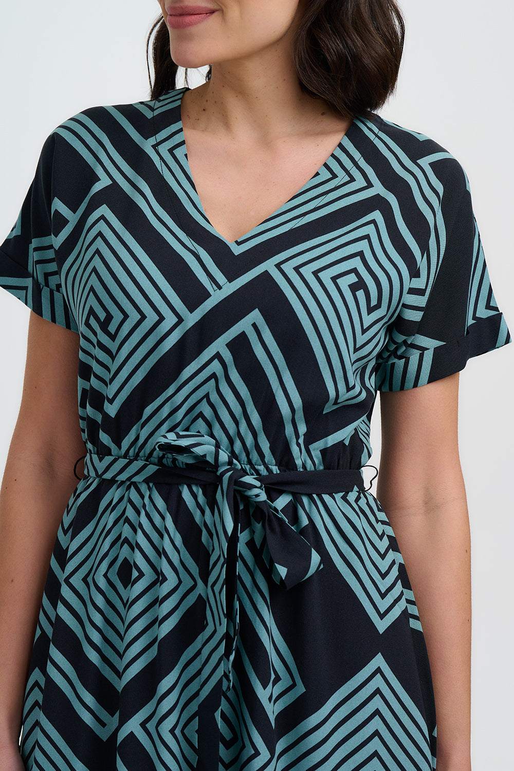 Woman wearing a black and teal patterned dress on a white background