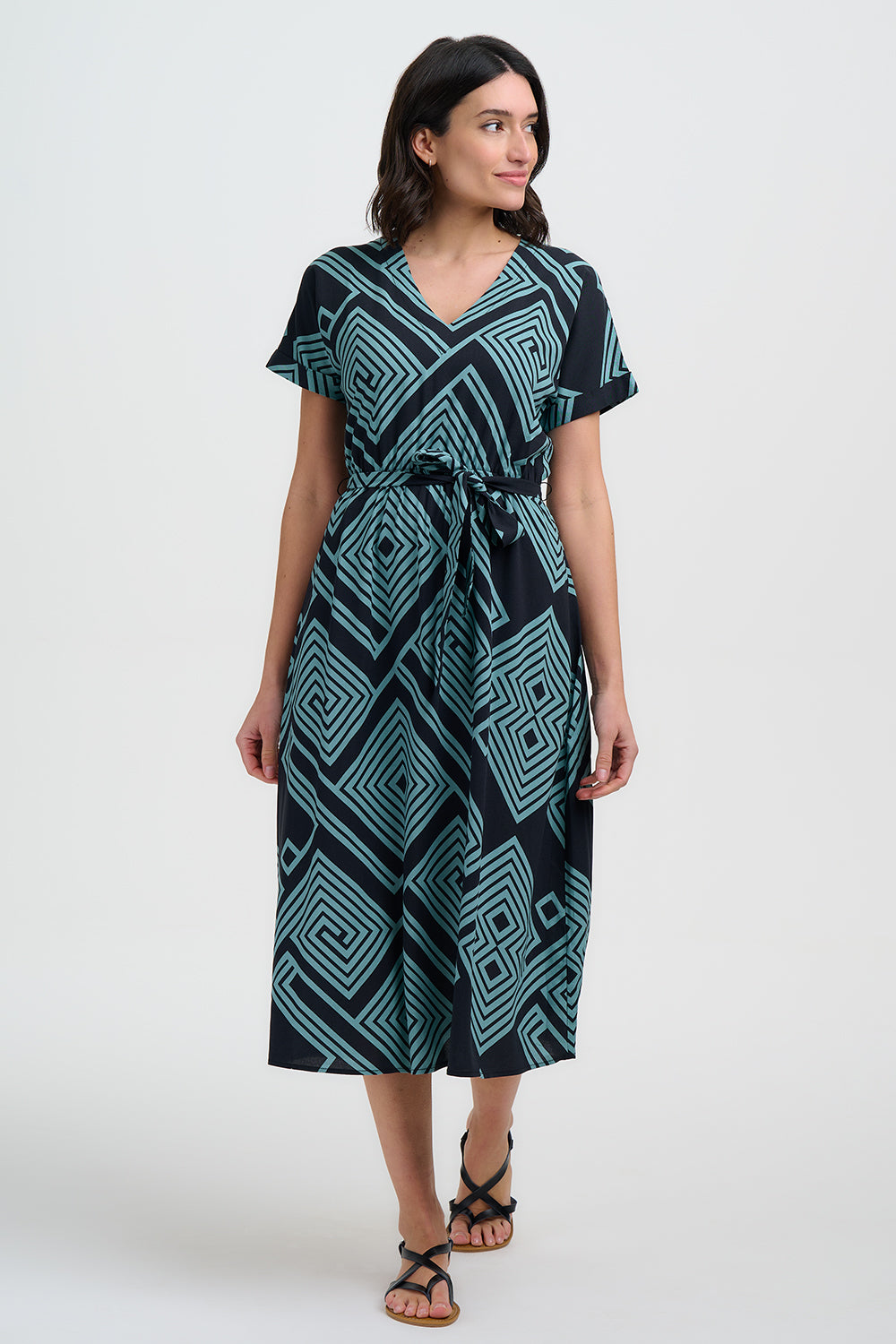 Woman wearing a black and teal patterned dress on a white background