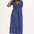 A model wearing a midi length dress with a shirred bodice, short shirred sleeves, and a V-neck. The dress has a geometric pattern with horizontal lines in blue, purple, pink, and orange.
