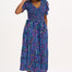 A model wearing a midi length dress with a shirred bodice, short shirred sleeves, and a V-neck. The dress has a geometric pattern with horizontal lines in blue, purple, pink, and orange.