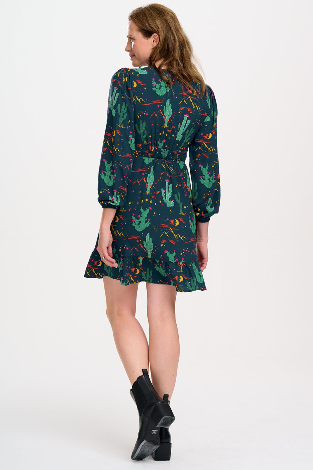 Woman wearing a dark green dress with cactus pattern on a white background