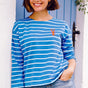 A woman wearing a French blue Breton top with white stripes and a detailed embroidered lobster on the chest, paired with casual jeans.