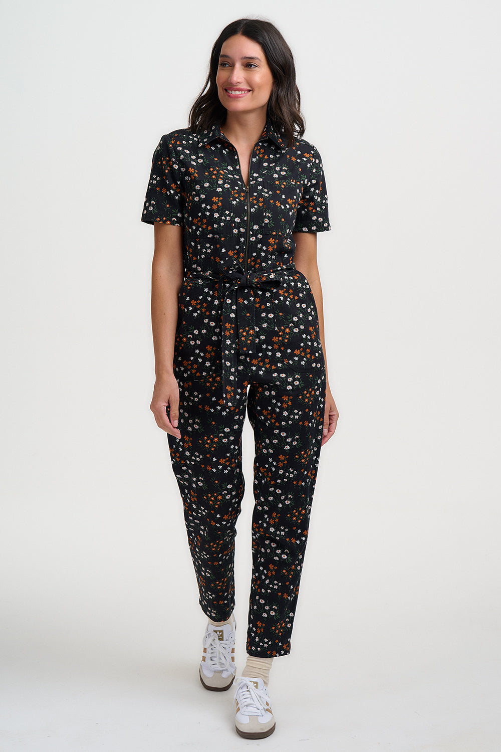 Woman wearing a black floral jumpsuit on a white background