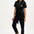A woman wearing a black boilersuit with a leopard pocket, paired with light-colored sneakers.