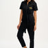 A woman wearing a black boilersuit with a leopard pocket, paired with light-colored sneakers.