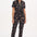 A person wearing a black and tan leopard print boilersuit with a tailored shape, half sleeve shirt upper, and straight legs.