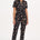 A person wearing a black and tan leopard print boilersuit with a tailored shape, half sleeve shirt upper, and straight legs.