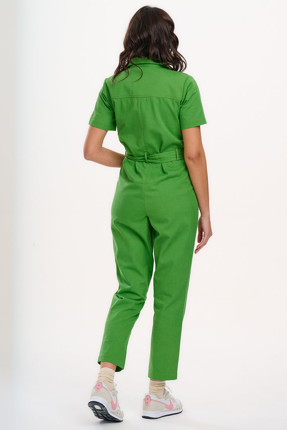 A model wearing a green boilersuit with rainbow flower embroidery on the chest pocket, featuring a half sleeve shirt upper, straight legs, and an exposed front zip.