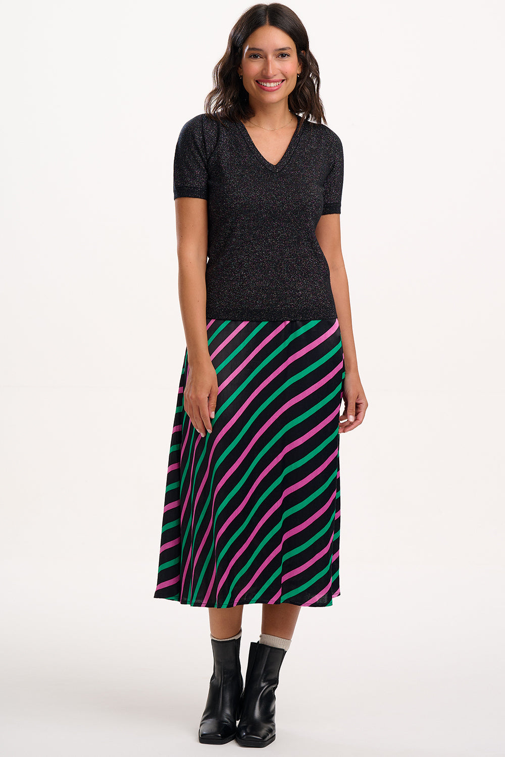 Woman wearing a black top and colorful striped skirt on a white background