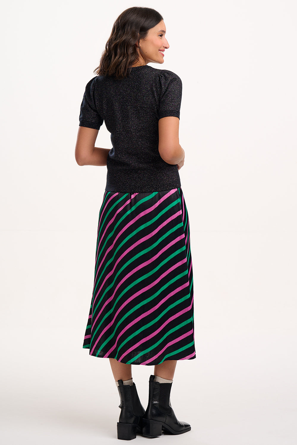 Woman wearing a black top and colorful striped skirt on a white background