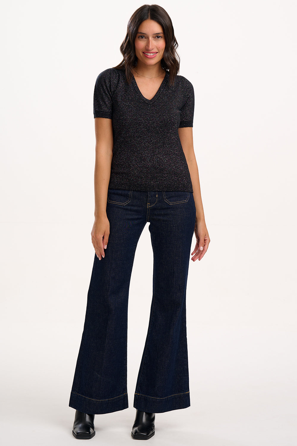 Woman wearing a dark gray t-shirt and dark blue jeans on a white background