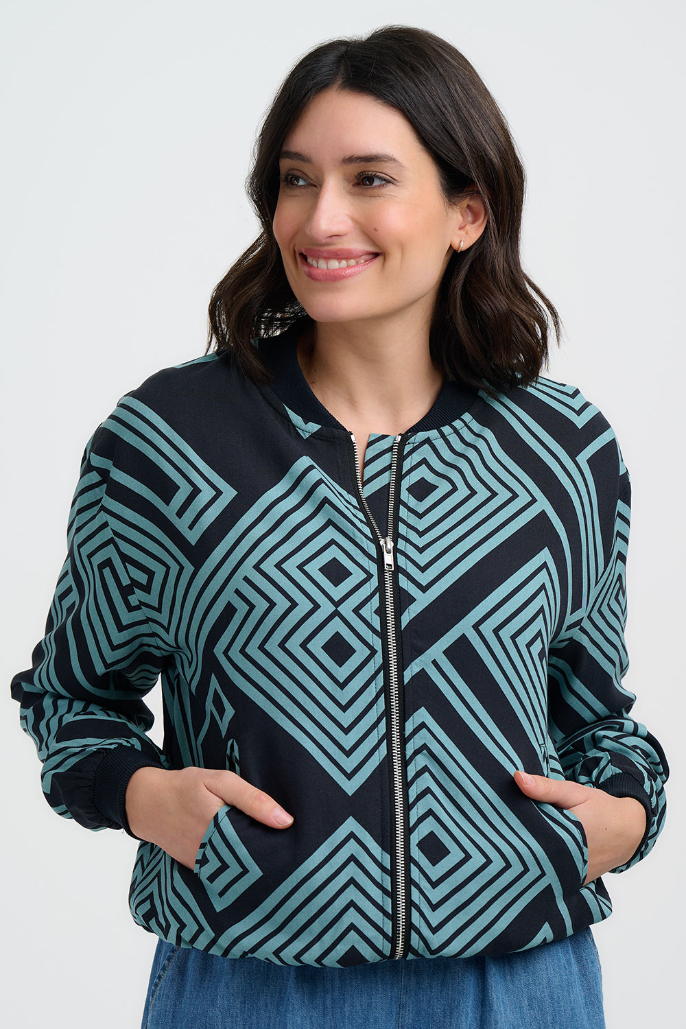 Woman wearing a black and teal patterned jacket on a white background
