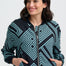 Woman wearing a black and teal patterned jacket on a white background