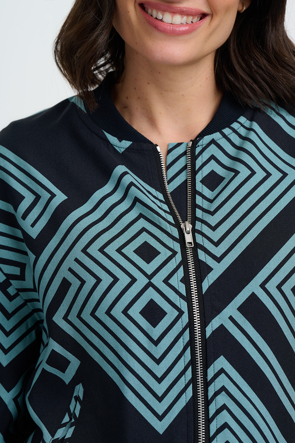 Close-up of a person wearing a black and blue geometric patterned jacket with a zipper.