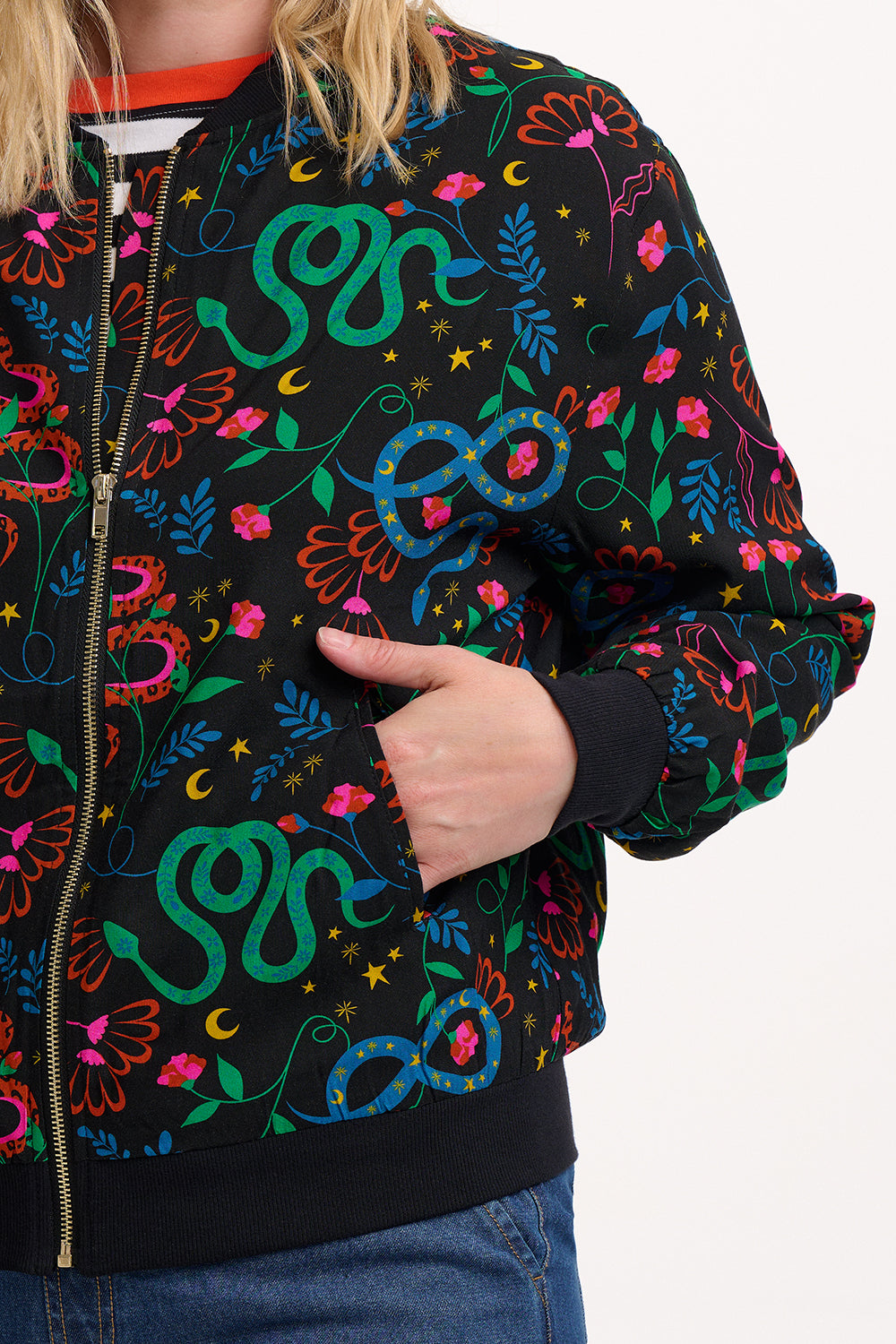 Person wearing a colorful patterned jacket with snake designs on a black background