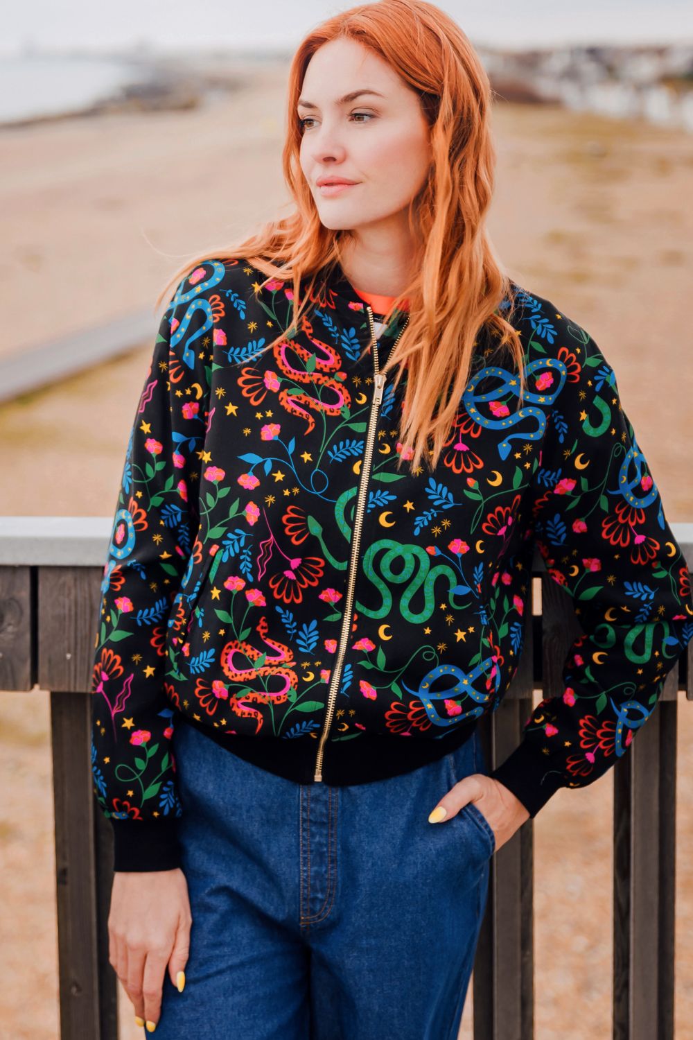 Person wearing a colorful embroidered jacket with a snake pattern outdoors.