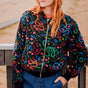 Person wearing a colorful embroidered jacket with a snake pattern outdoors.