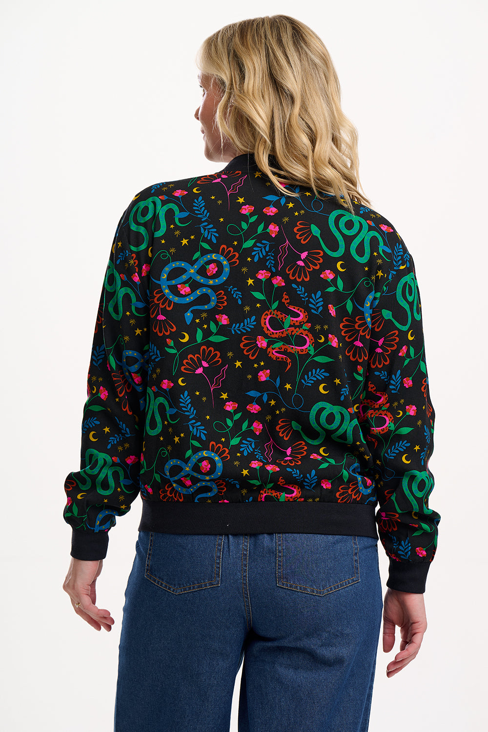 Person wearing a black bomber jacket with colorful snake pattern on a white background