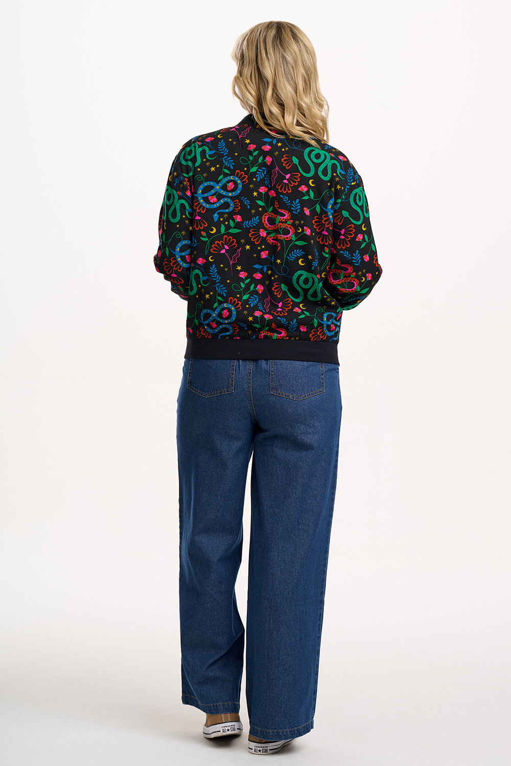Person wearing a colorful patterned shirt and blue jeans on a white background
