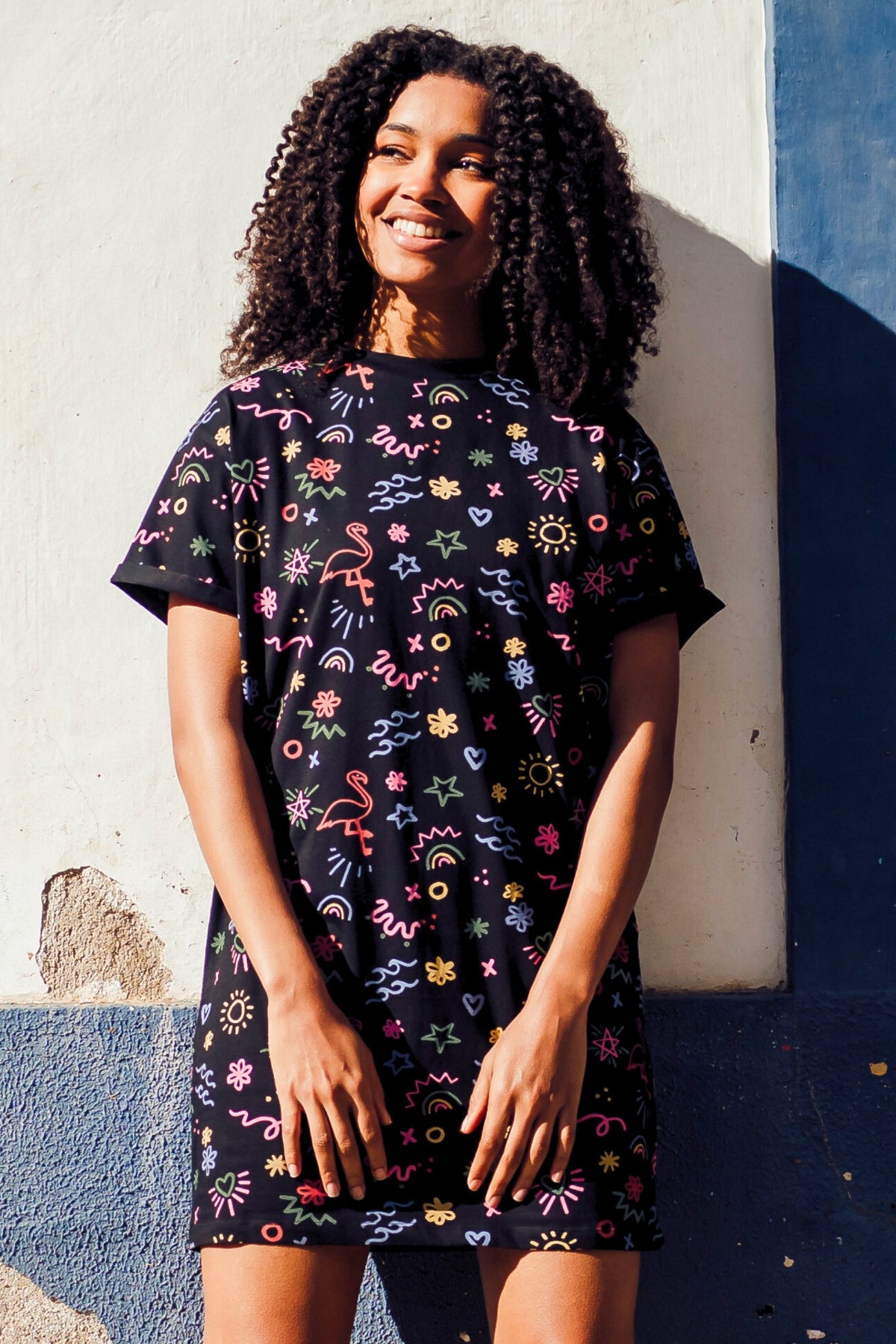 Person wearing a black dress with colorful floral patterns on a white background