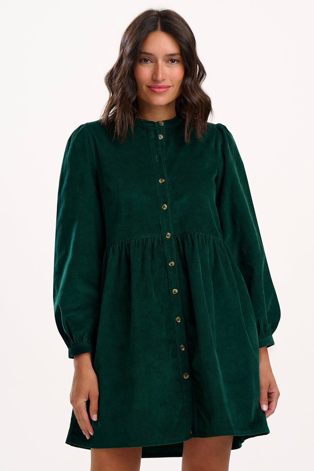 Model wearing green dress with long sleeves and buttons on a white background