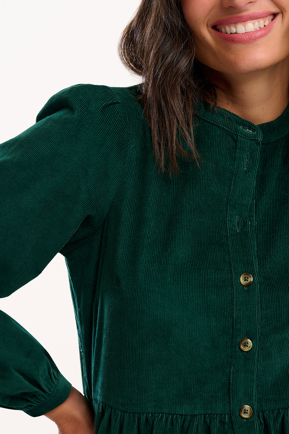 Model wearing green dress with long sleeves and buttons on a white background